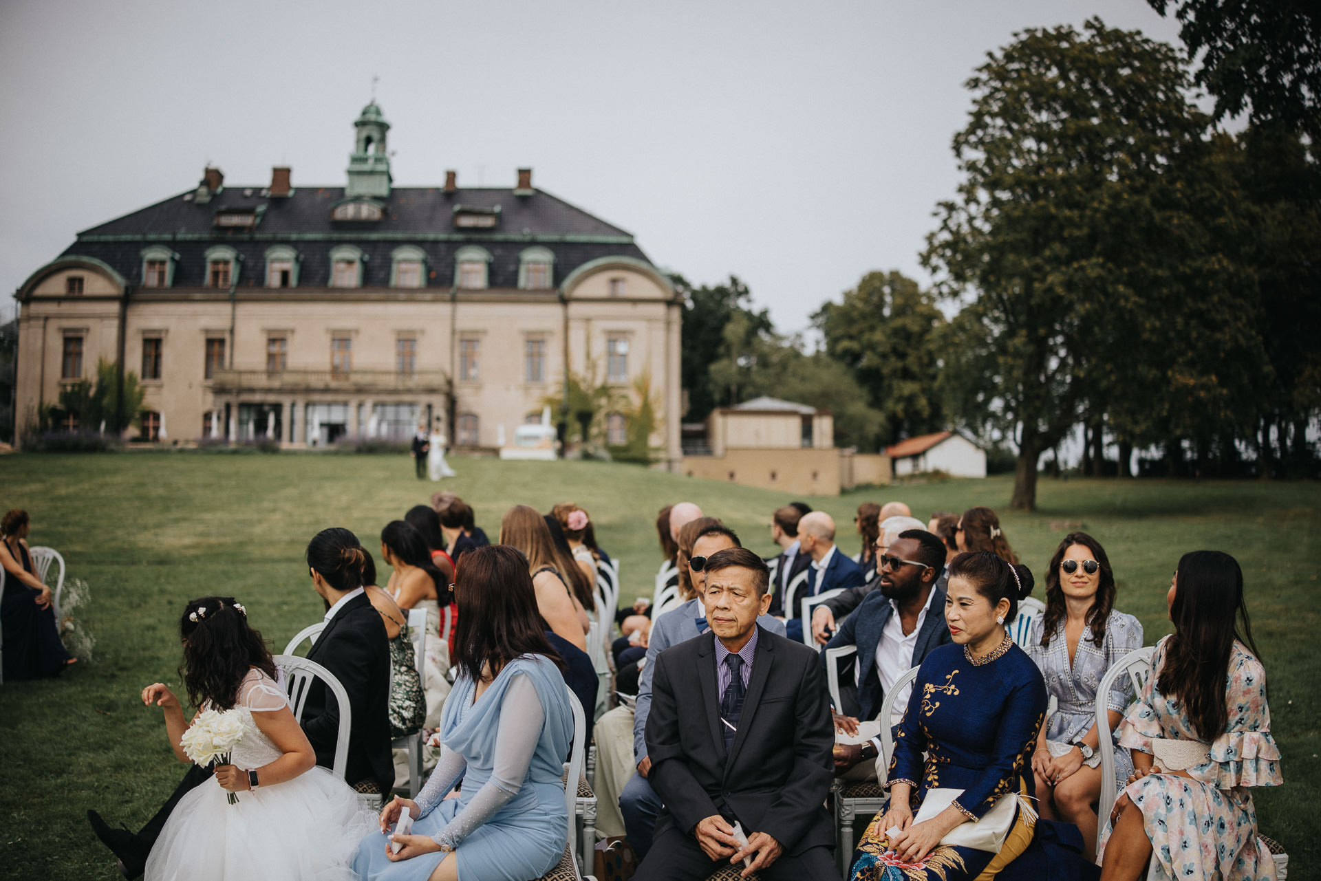 Bröllopsgäster samlade inför utomhusvigsel med Maryhill Estate i bakgrunden
