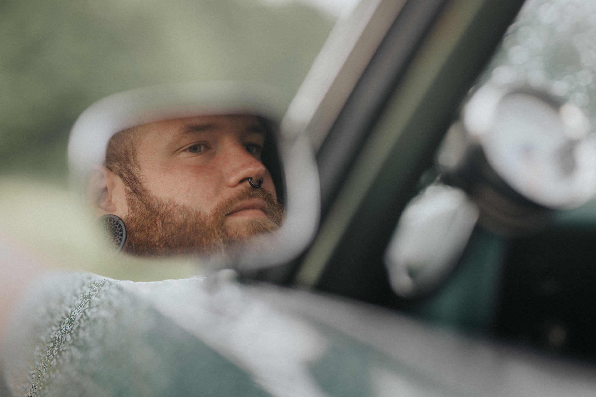 Konstnärligt bröllopsporträtt av brudgummen fotograferad genom backspegeln på en veteranbil